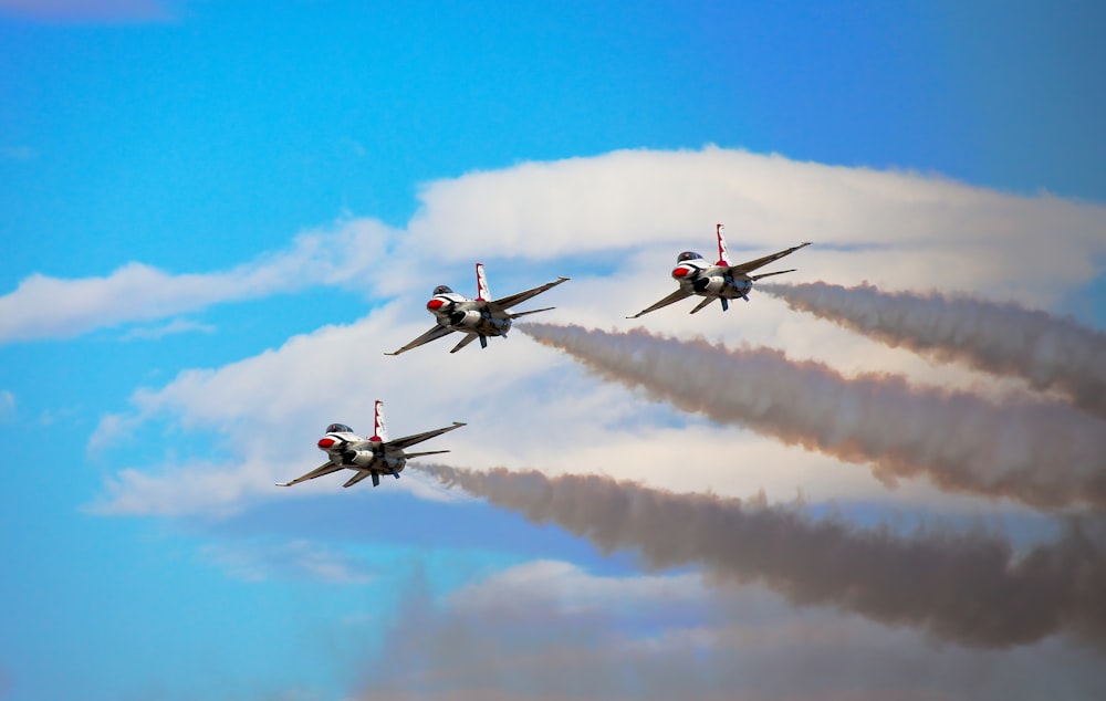 a group of fighter jets flying through a cloudy blue sky