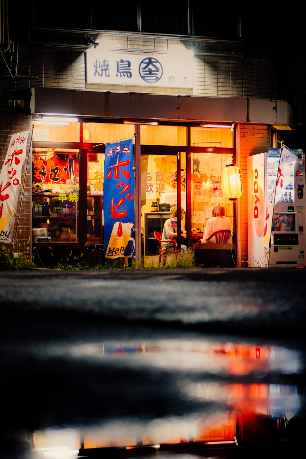 a store front at night with a reflection in the water