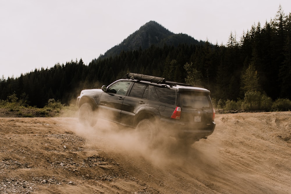 a jeep driving down a dirt road near a forest