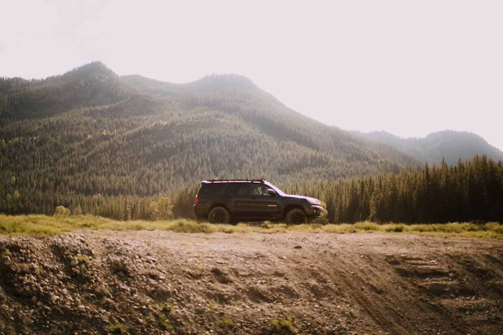 um jipe está estacionado em uma estrada de terra nas montanhas