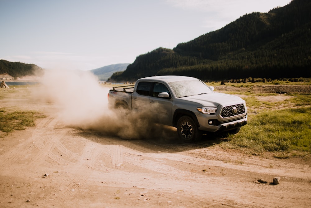 a pickup truck driving down a dirt road