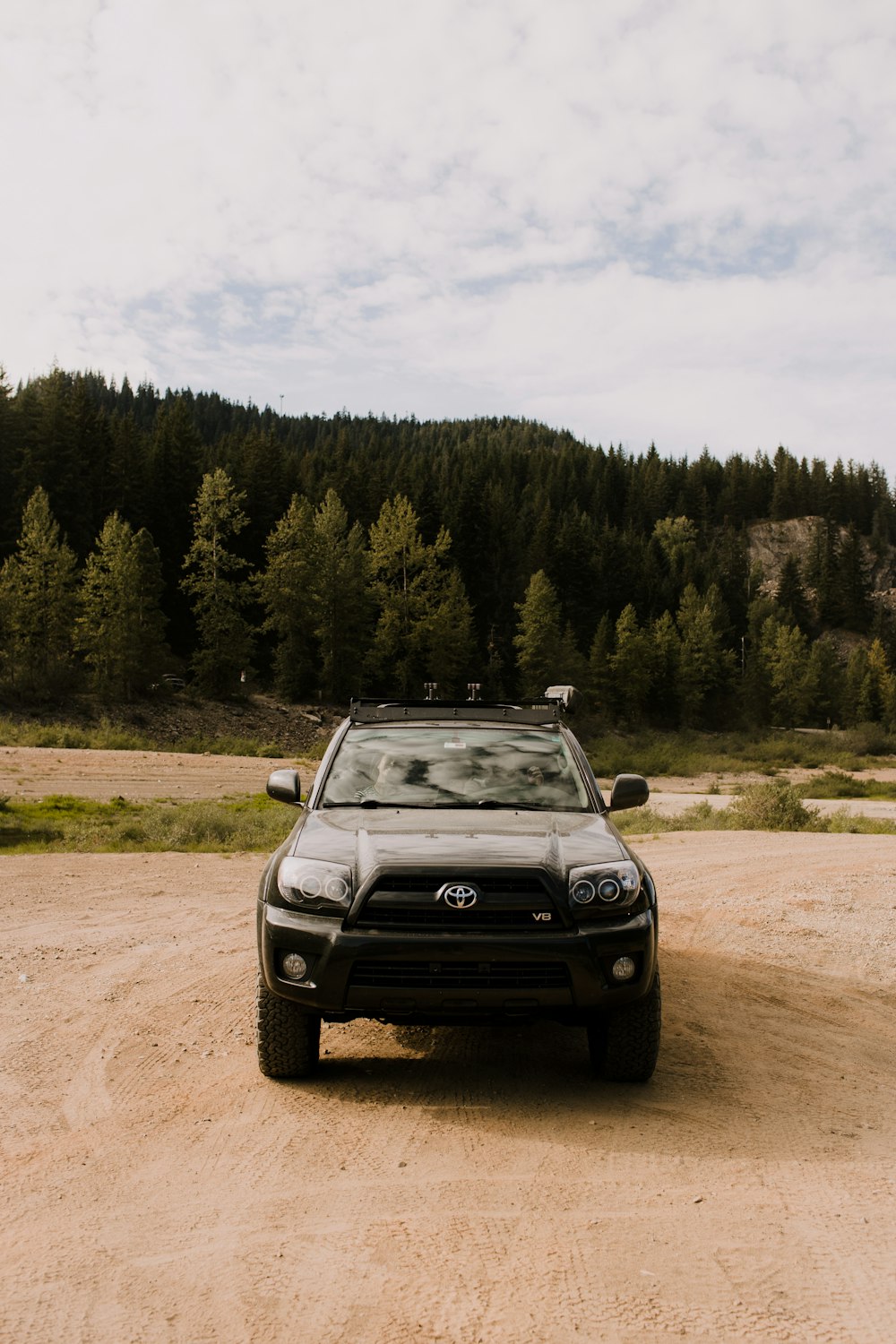 a truck parked on a dirt road in front of a forest