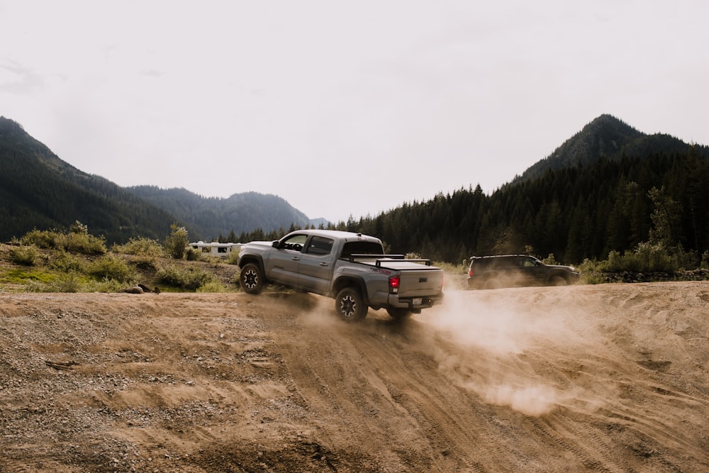 a pickup truck driving down a dirt road