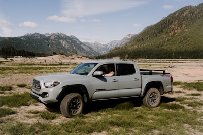 a truck parked in a field with mountains in the background