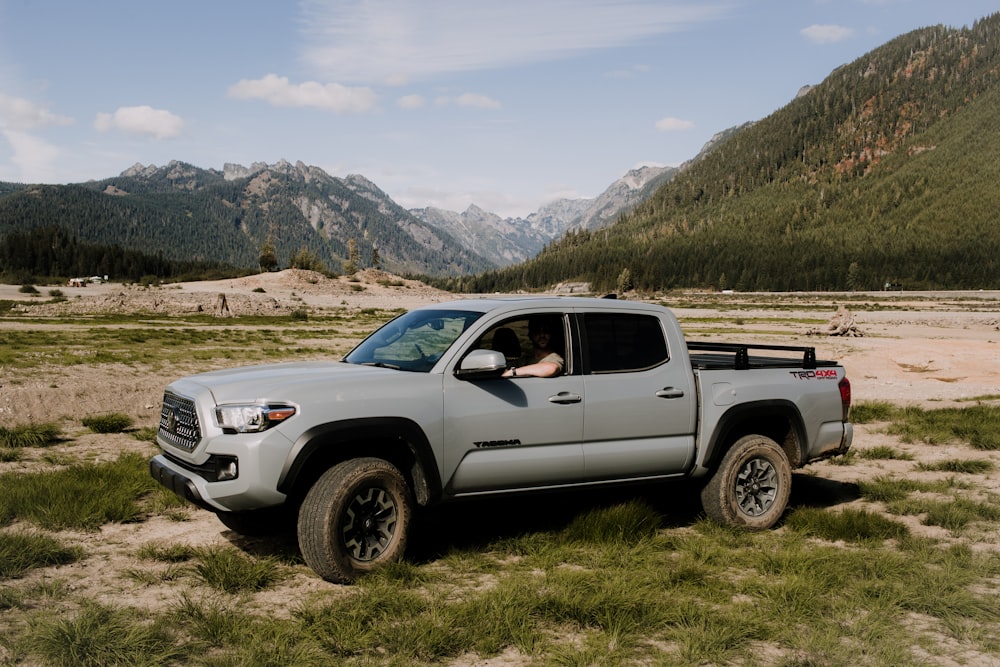 a truck parked in a field with mountains in the background