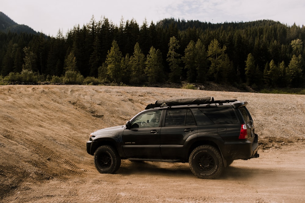 a black suv driving on a dirt road