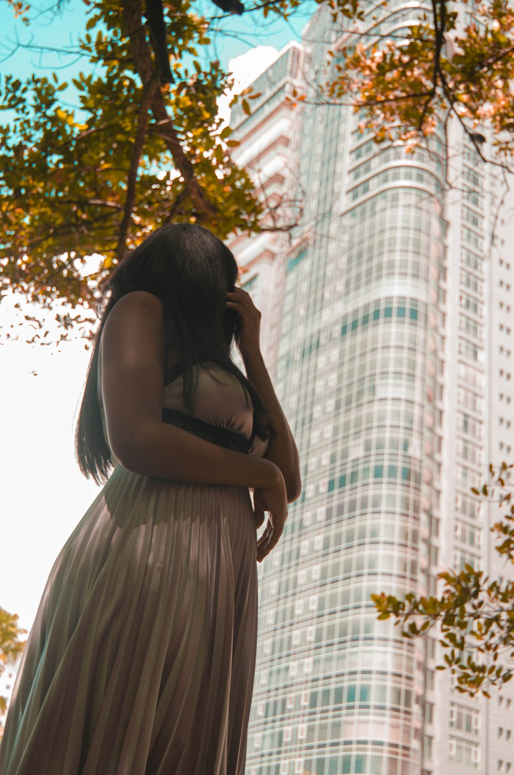 a woman standing in front of a tall building talking on a cell phone