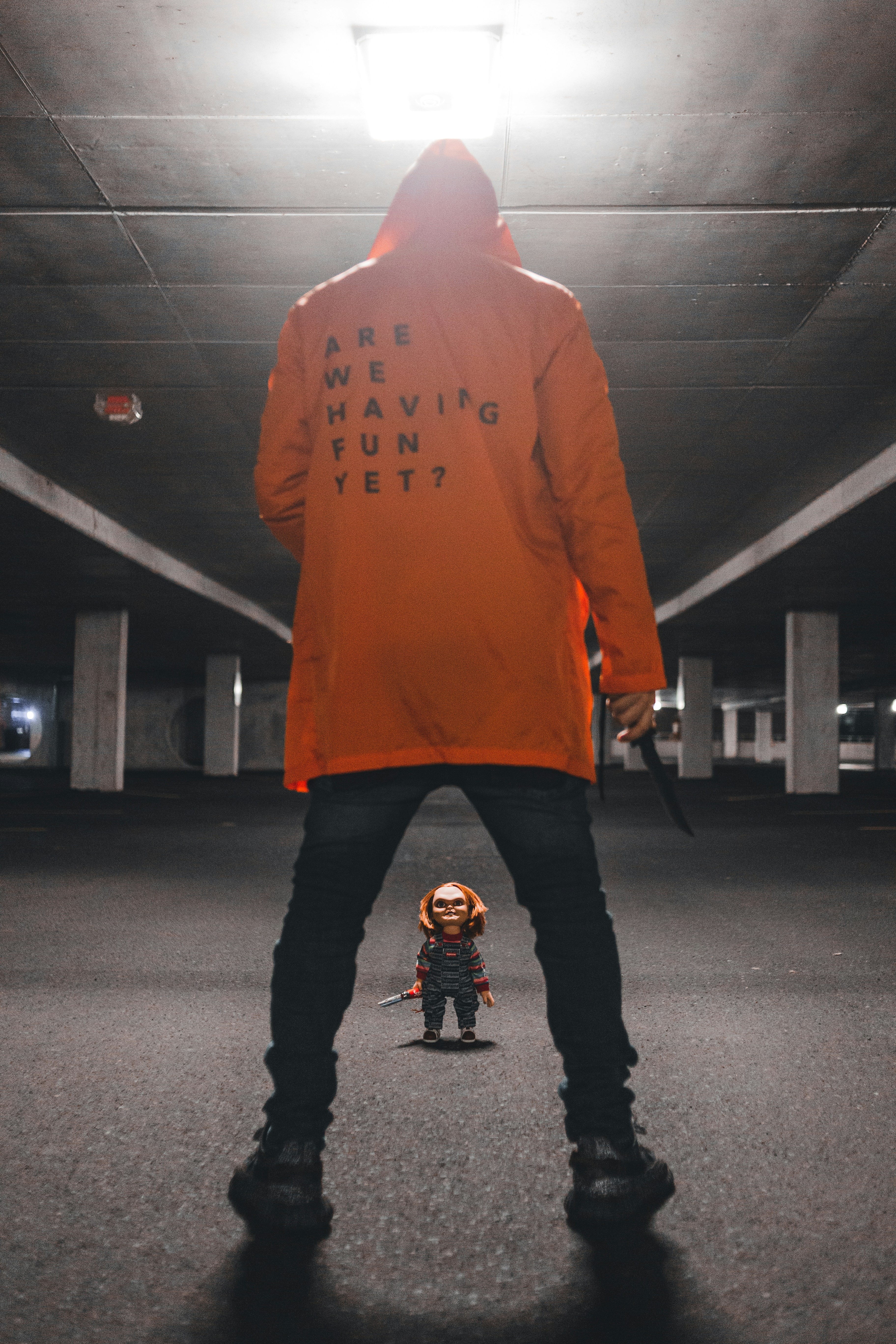 a man in an orange jacket standing in a parking garage
