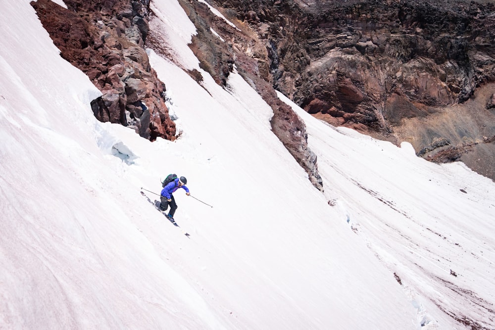 a man riding skis down the side of a snow covered slope