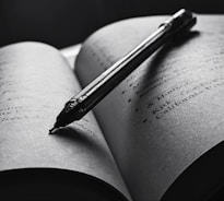 An open book with a pen resting on top, symbolizing the art of writing and storytelling.