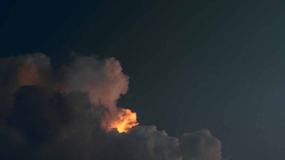 a jet flying through a cloudy sky at night