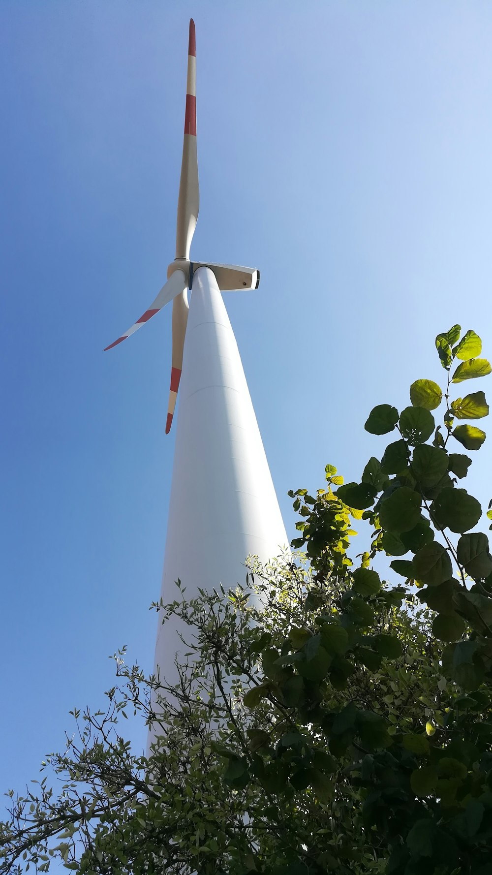 a large white wind turbine next to a tree