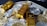 Several gold bars are placed on top of a pile of bitcoin coins and US dollar bills, indicating a scene of wealth and finance.