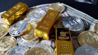 Several gold bars are placed on top of a pile of bitcoin coins and US dollar bills, indicating a scene of wealth and finance.