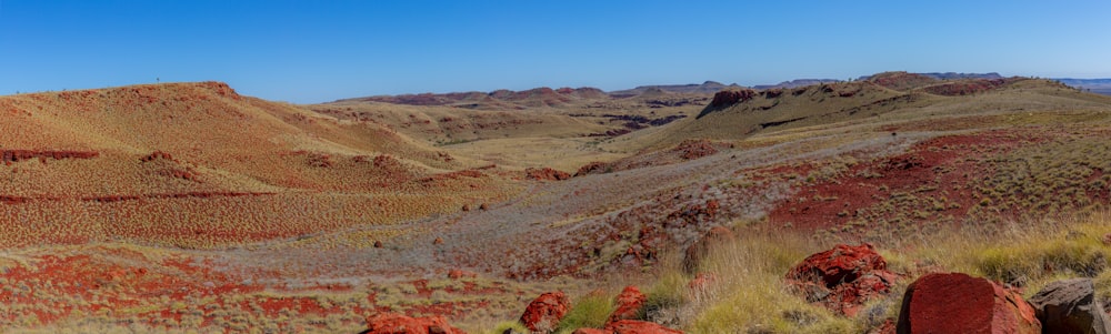 a view of a mountain range with red rocks in the foreground