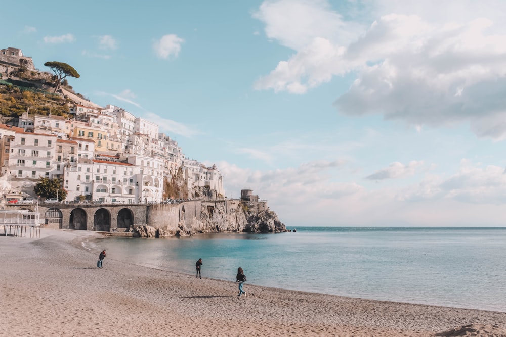 a couple of people walking on a beach next to the ocean