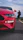 Close-up of a woman reviewing a sports car with a camera crew filming behind her.