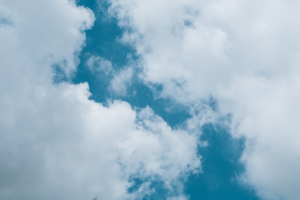 a plane flying through a cloudy blue sky