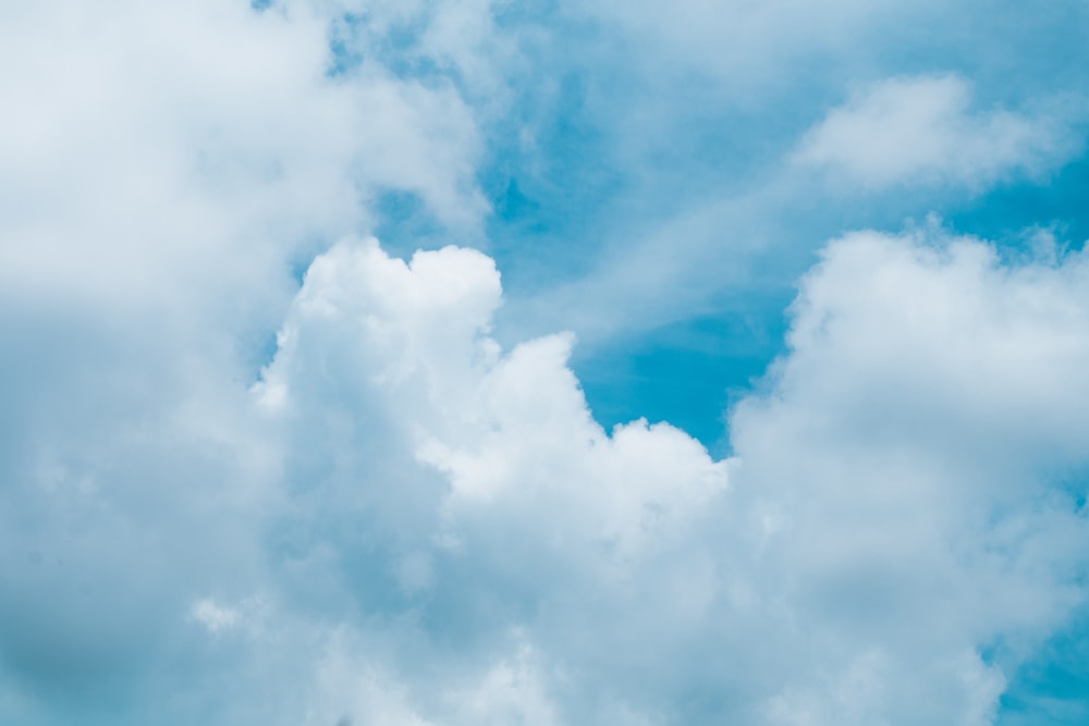 a plane flying through a cloudy blue sky