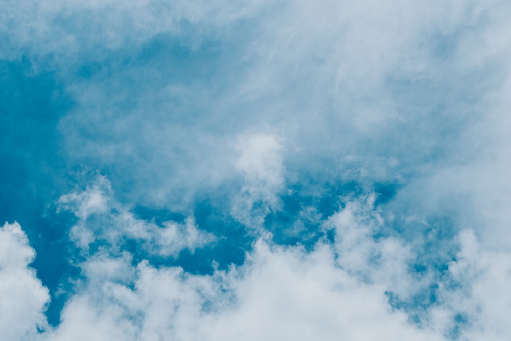 a plane flying through a cloudy blue sky