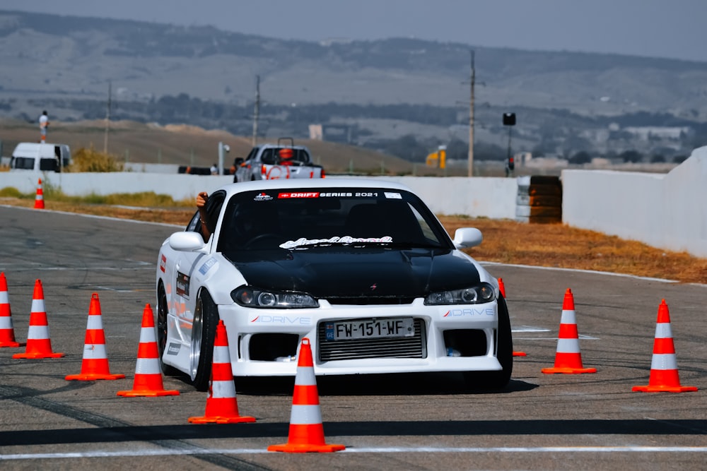 a white car driving around orange cones on a race track