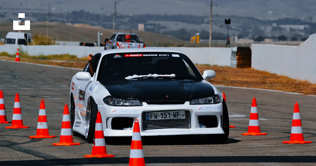 A white car driving around orange cones on a race track photo – Free ...