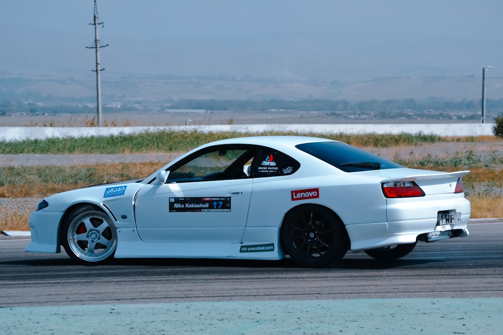 a white car driving down a race track