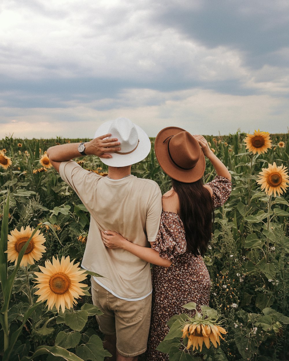 Un hombre y una mujer parados en un campo de girasoles