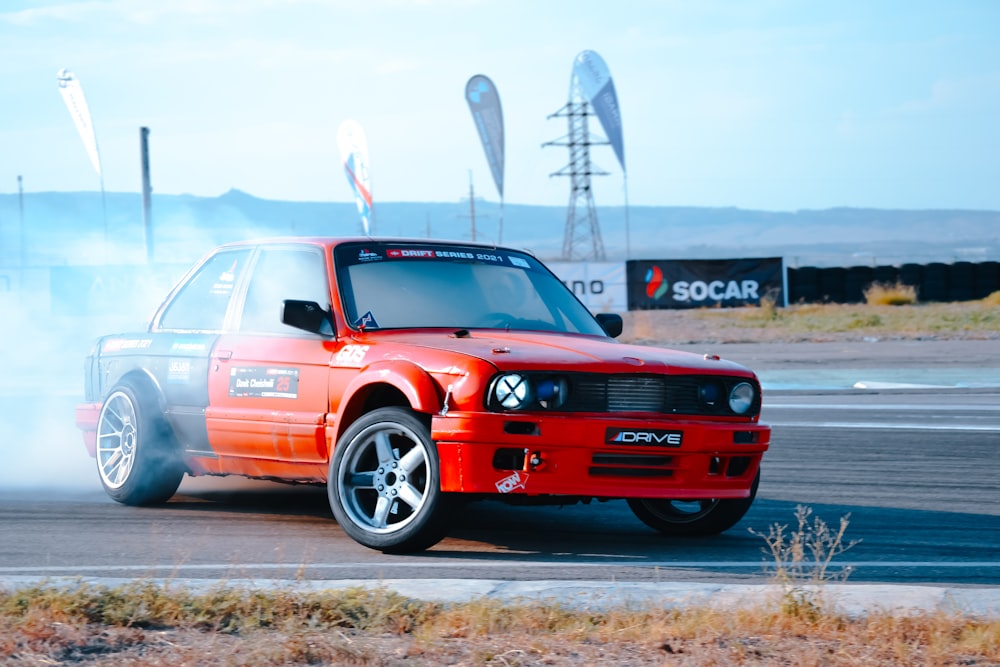 a red car driving on a track with smoke coming out of it