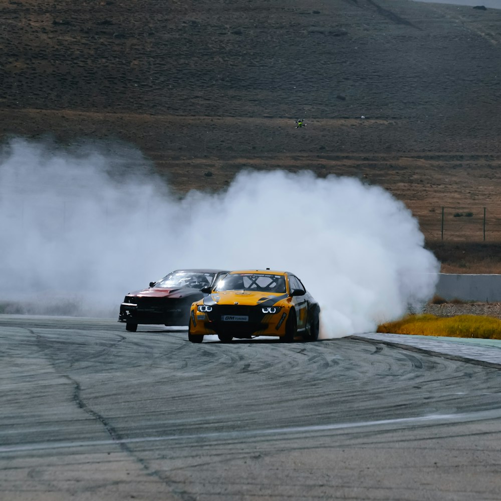 two cars driving on a race track with smoke coming out of them
