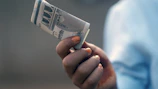 a person holding a rolled up money in their hand