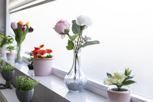 A sunlit window sill decorated with small potted plants and colorful glass ornaments.