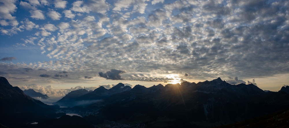 the sun is shining through the clouds over the mountains