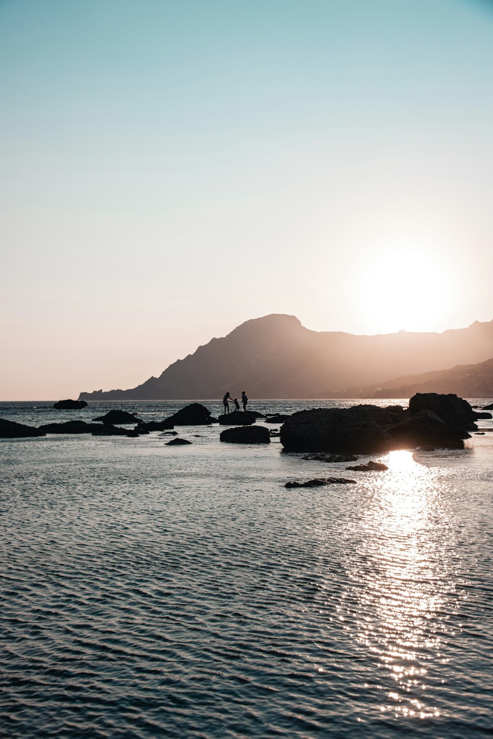 a couple of people standing on top of a rocky beach