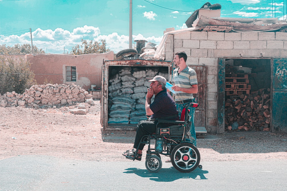 a man in a wheel chair talking to another man