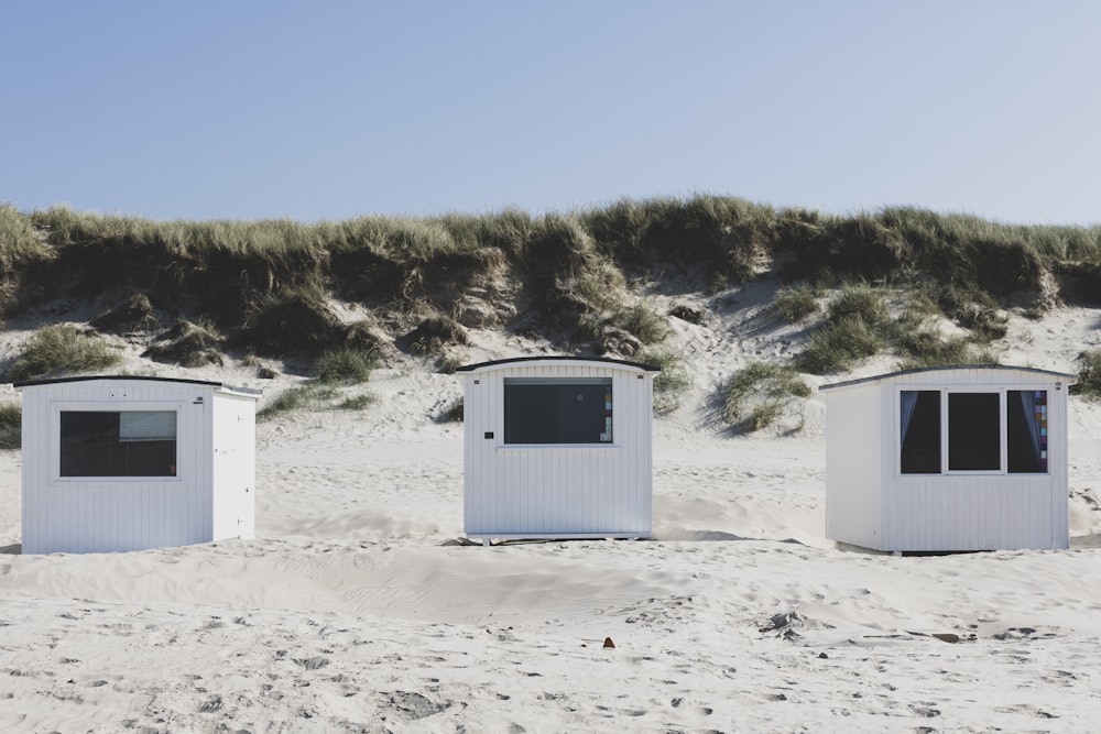 a row of white beach huts sitting on top of a sandy beach