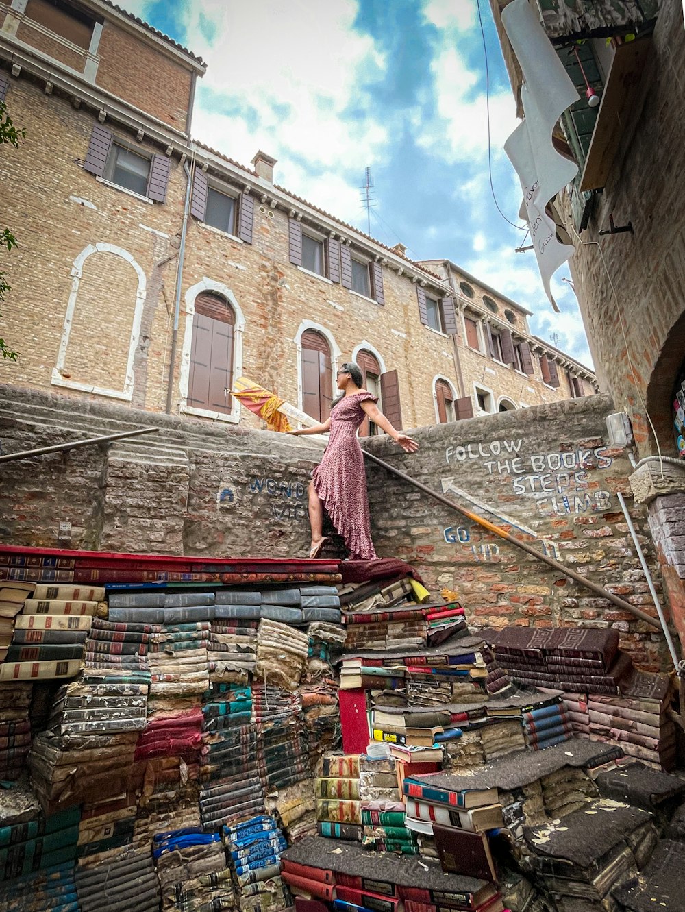 a woman in a pink dress standing on a pile of books