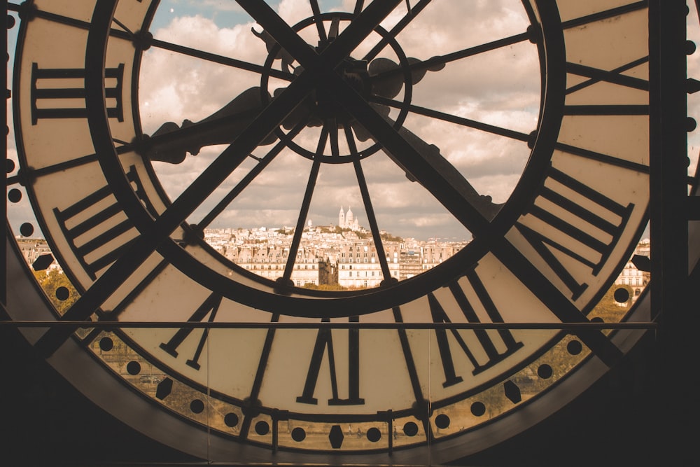 a large clock with roman numerals and a city in the background