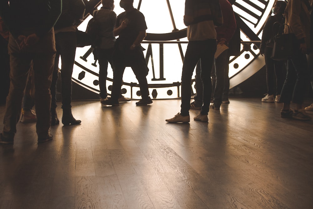 a group of people standing in front of a large clock