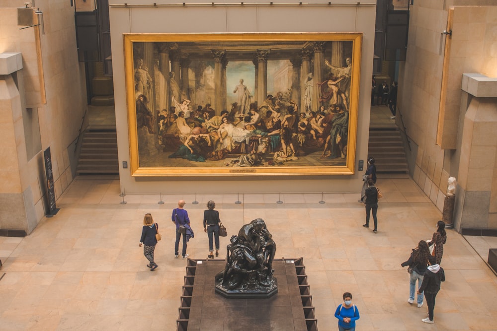 um grupo de pessoas olhando para uma pintura em um museu