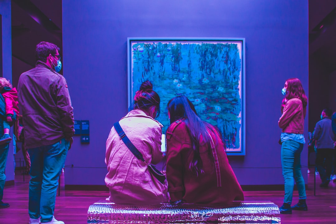 two people sitting on a bench in front of a painting,