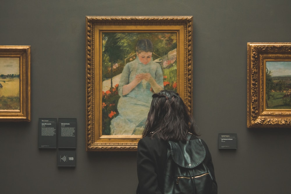 uma mulher olhando para uma pintura em um museu