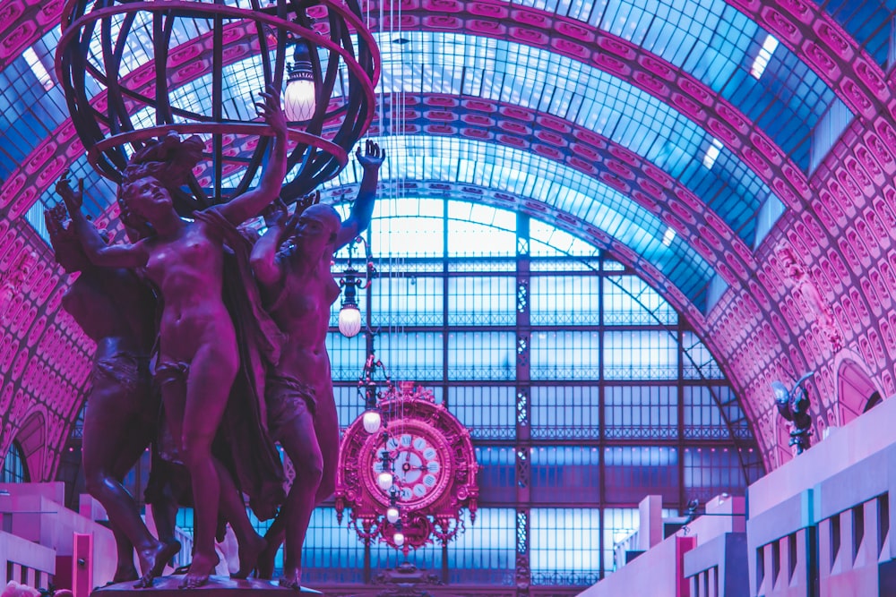 a statue of two men holding a ball in a building