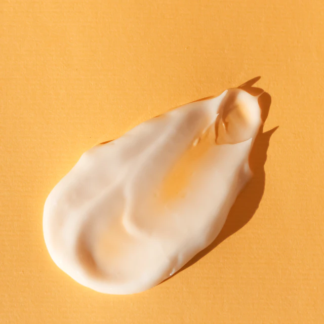 A close-up of a smear of white cream on a yellow surface