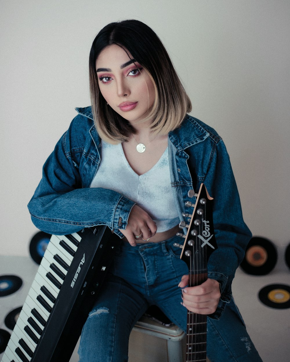 a woman sitting on top of a stool holding a guitar