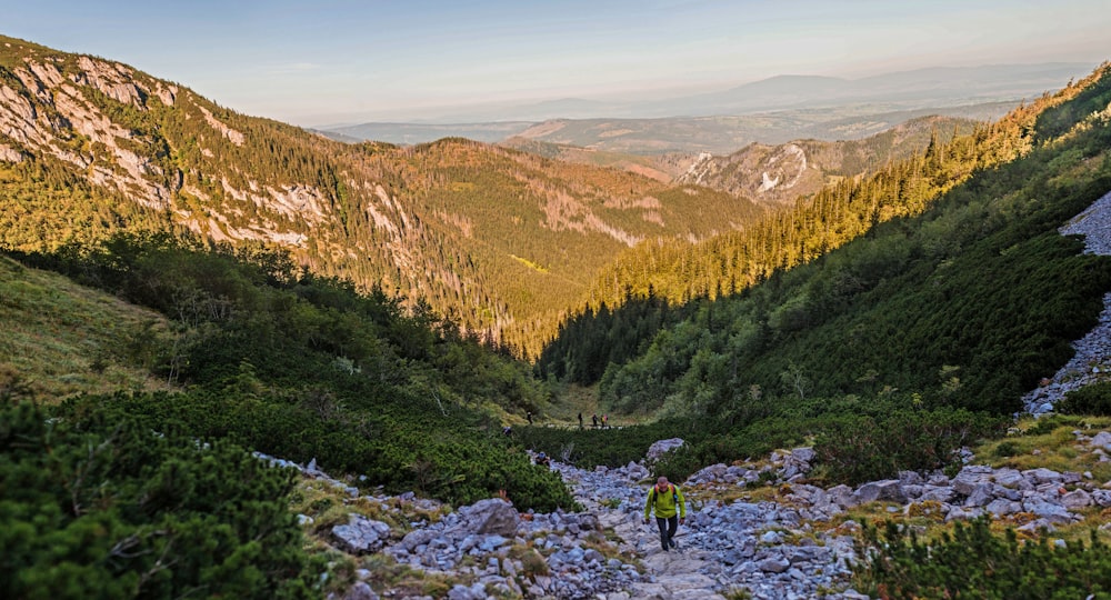 a man standing on a rocky trail in the mountains