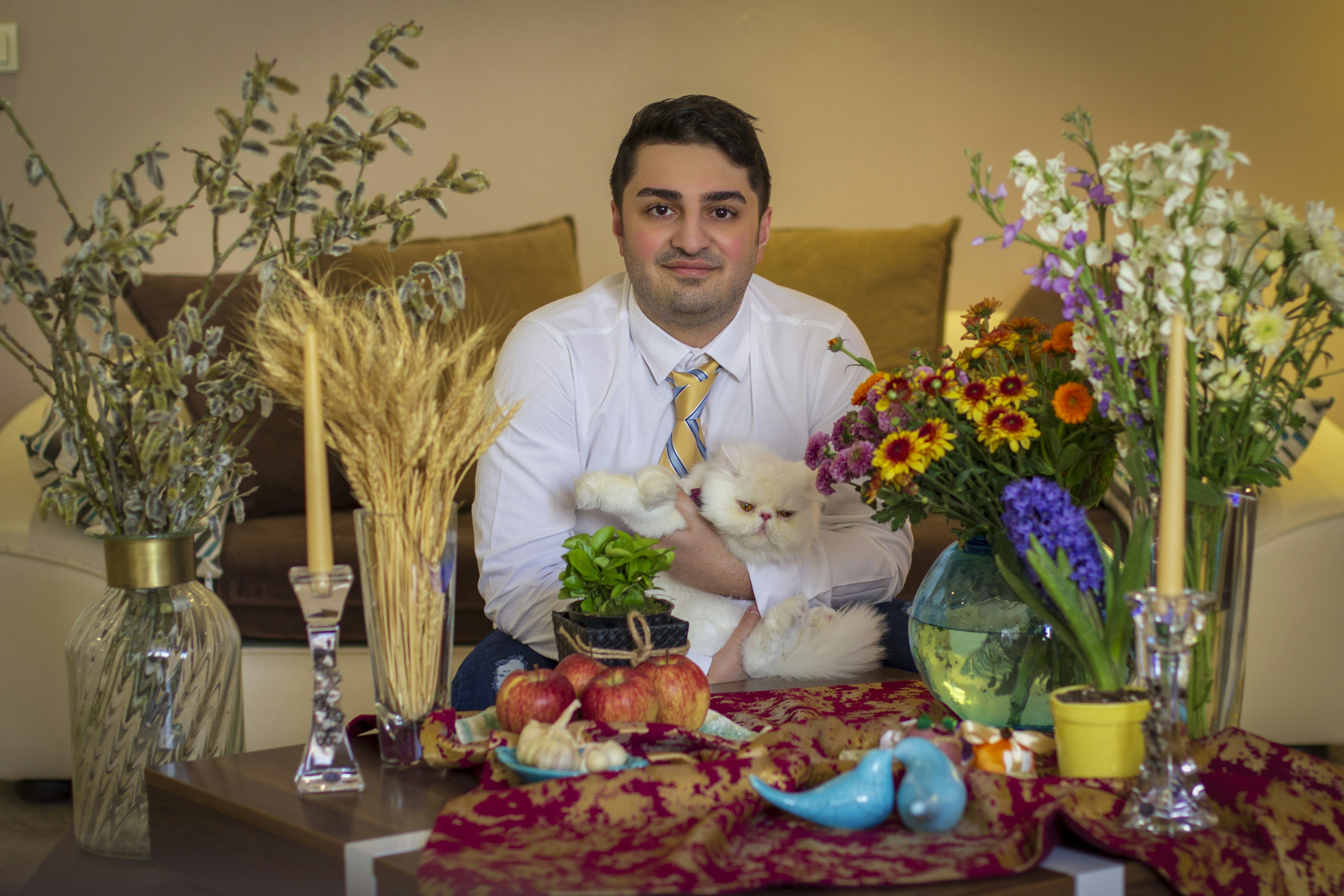 a man sitting on a couch holding a small white dog
