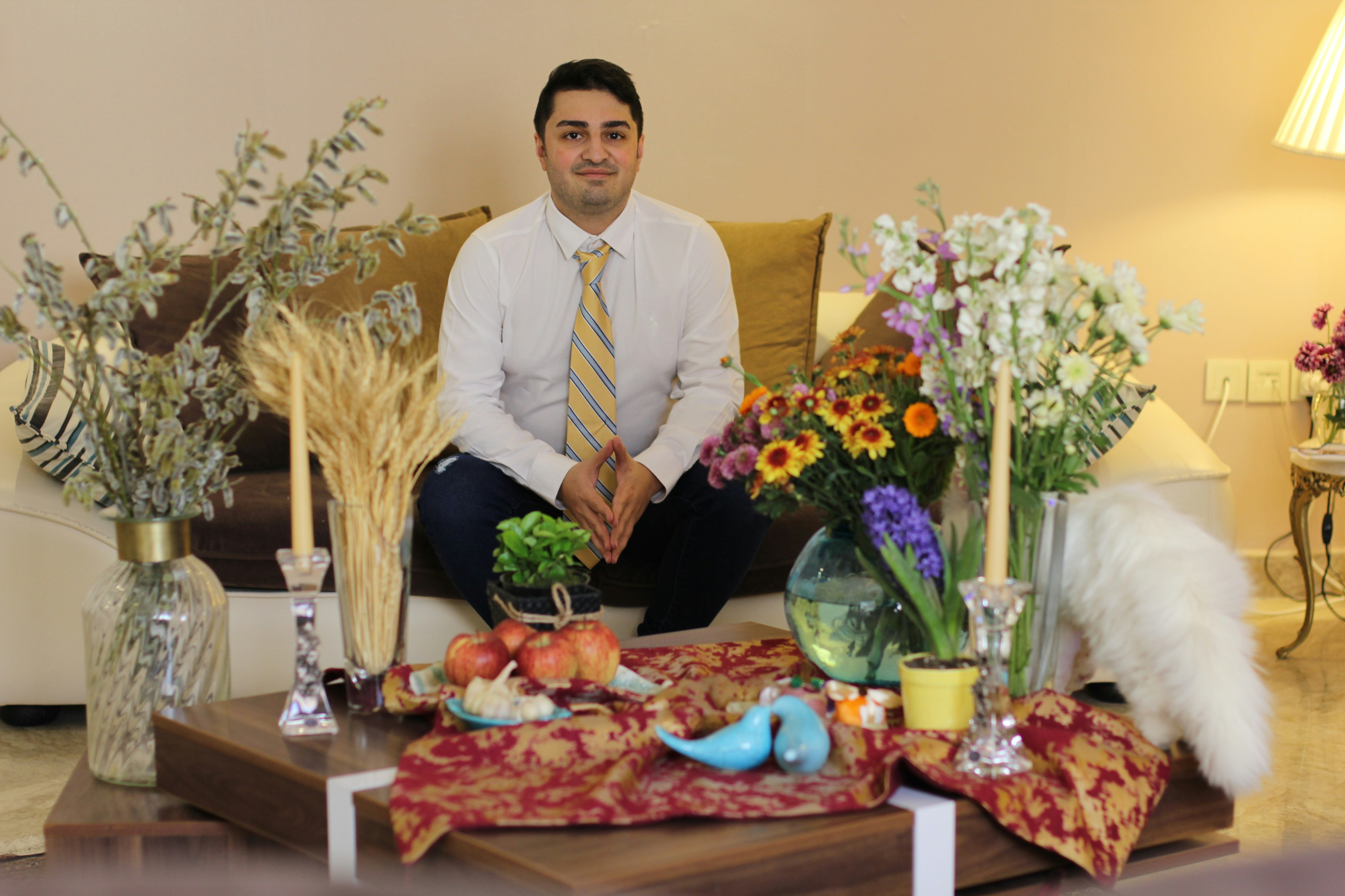 a man sitting on a couch in front of a bunch of flowers