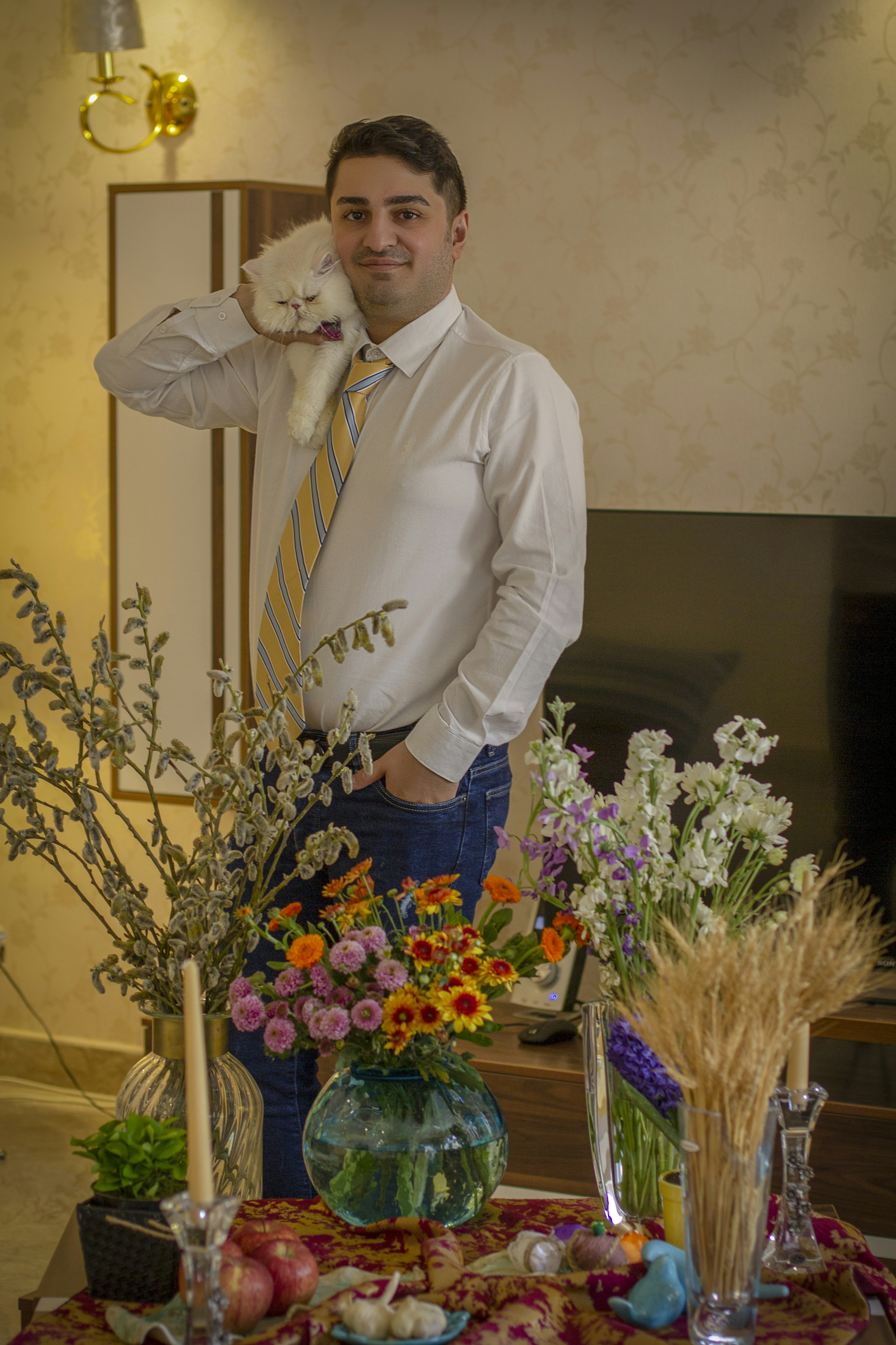 a man standing next to a table with flowers and vases on it