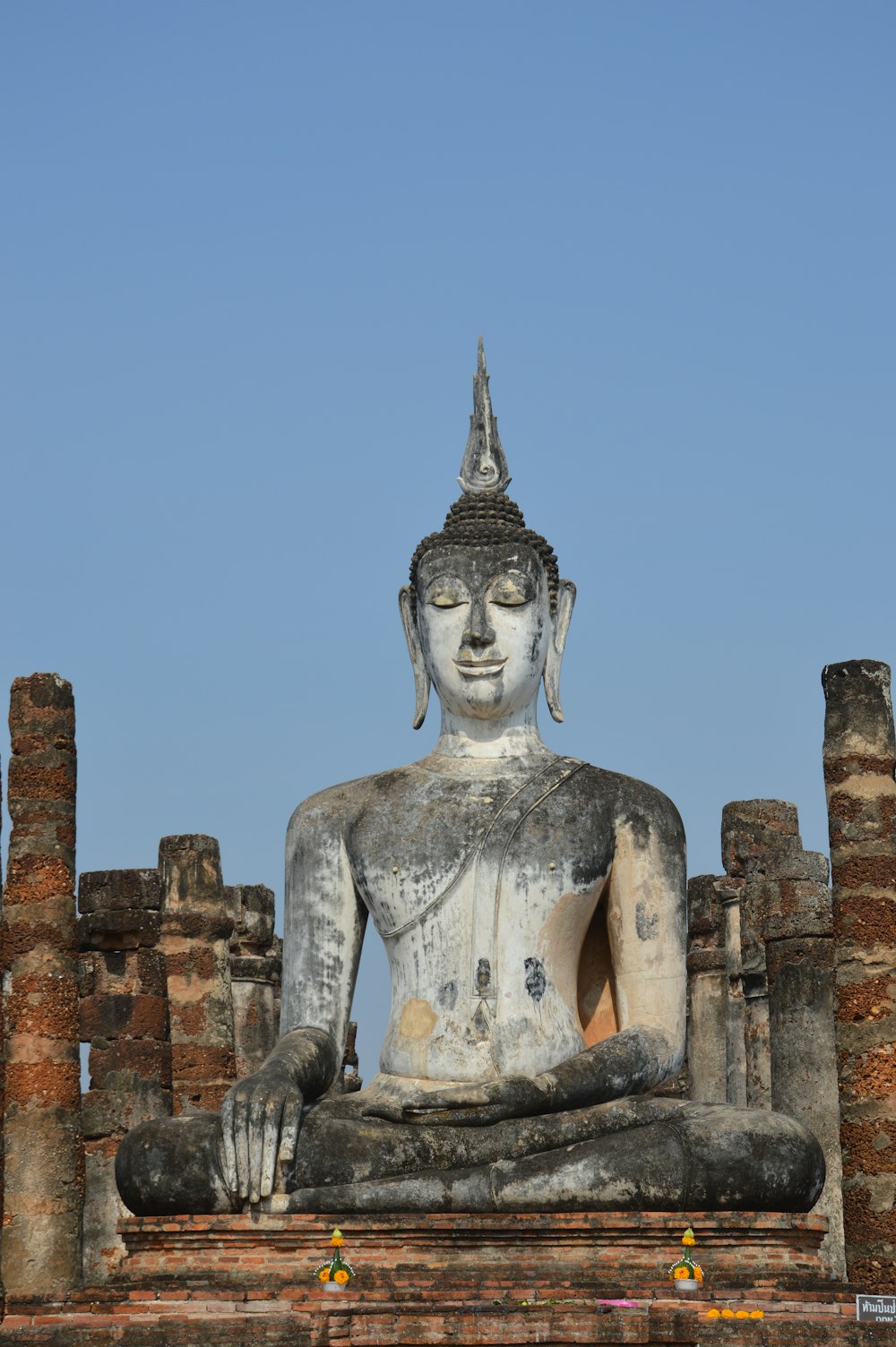 a statue of a buddha sitting on top of a brick wall